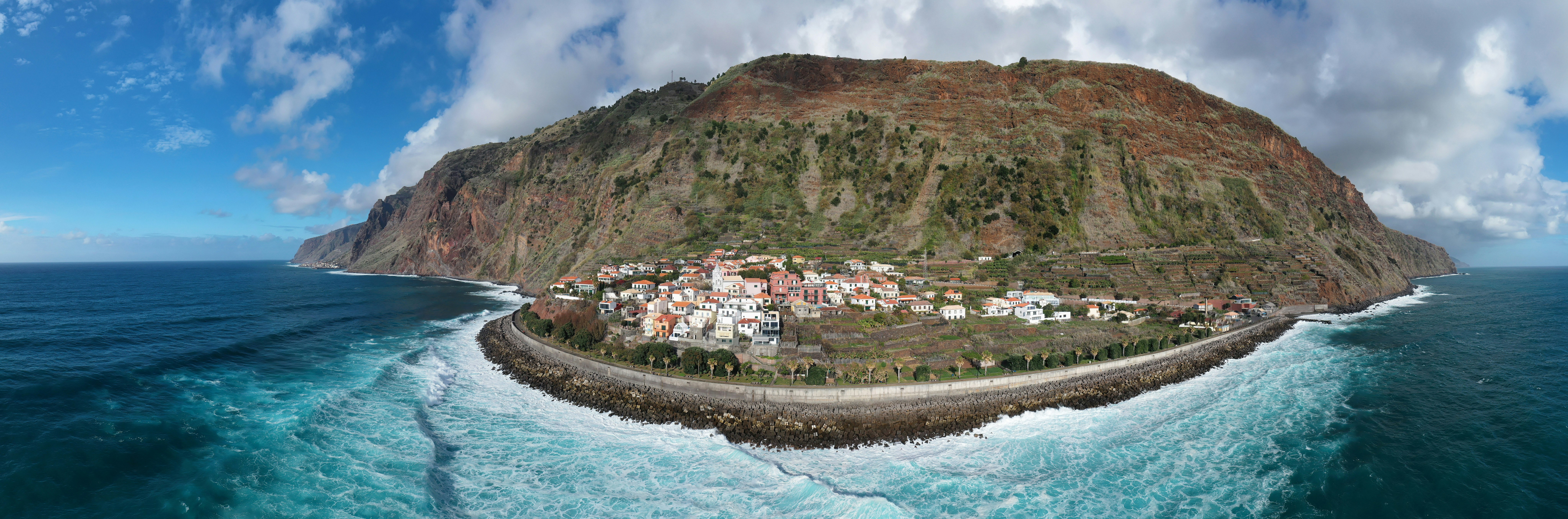 houses on mountain beside body of water during daytime